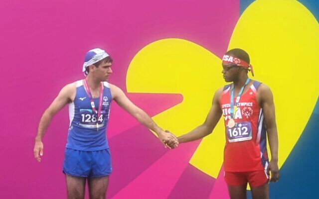 Le coureur Saar Buchbinder, à gauche, tient la main de l'athlète américain Trasean Singletary lors de la cérémonie de remise des médailles des Jeux spéciaux à Berlin, le 19 juin 2023. (Autorisation)