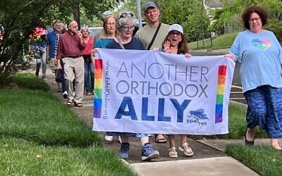 Des membres et des alliés d'Eshel, un groupe de défense des juifs orthodoxes LGBTQ et de leurs familles, défilent à Highland Park, dans le New Jersey, alors que les drapeaux de la Fierté sont rétablis dans une rue publique après avoir été retirés à la demande de rabbins orthodoxes, le 26 juin 2023. (Crédit : Autorisation d'Eshel/JTA)