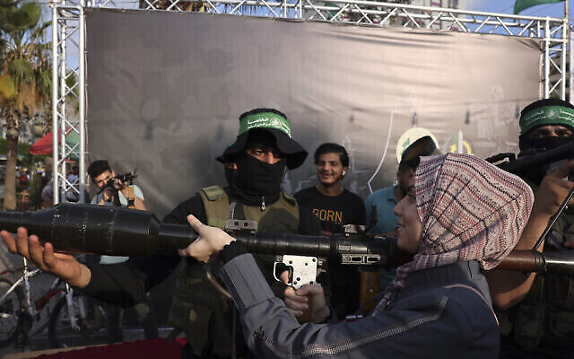Des enfants palestiniens manient des armes lors d'une exposition des armes du groupe terroriste du Hamas de Gaza dans la ville de Gaza, le 30 juin 2023. (Crédit : Mohammed ABED / AFP)