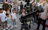 Des enfants gazaouis posant pour des photos souvenirs avec des armes lors d'une exposition des armes du groupe terroriste du Hamas de Gaza, à Gaza-City, le 30 juin 2023. (Crédit : Mohammed Abed/AFP)