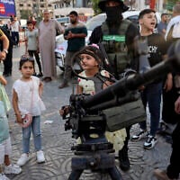 Des enfants gazaouis posant pour des photos souvenirs avec des armes lors d'une exposition des armes du groupe terroriste du Hamas de Gaza, à Gaza-City, le 30 juin 2023. (Crédit : Mohammed Abed/AFP)