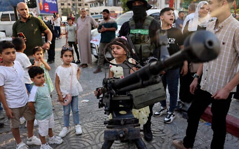 Des enfants gazaouis posant pour des photos souvenirs avec des armes lors d'une exposition des armes du groupe terroriste du Hamas de Gaza, à Gaza-City, le 30 juin 2023. (Crédit : Mohammed Abed/AFP)