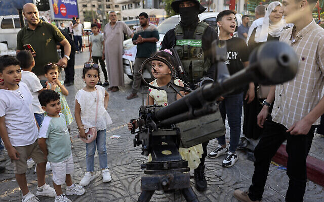Des enfants palestiniens posent pour des photos souvenirs avec des armes lors d'une exposition des armes du groupe terroriste du Hamas de Gaza dans la ville de Gaza, le 30 juin 2023. (Crédit : Mohammed ABED / AFP)