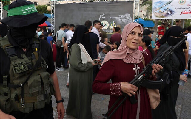 Des Palestiniens posent pour des photos souvenirs avec des armes lors d'une exposition des armes du groupe terroriste du Hamas de Gaza dans la ville de Gaza, le 30 juin 2023. (Crédit : Mohammed ABED / AFP)
