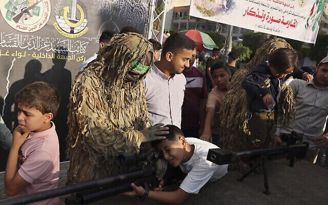 Des enfants palestiniens manient des armes lors d'une exposition des armes du groupe terroriste du Hamas de Gaza dans la ville de Gaza, le 30 juin 2023. (Crédit : Mohammed ABED / AFP)