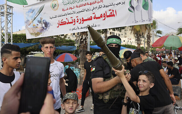 Des enfants palestiniens manient des armes lors d'une exposition des armes du groupe terroriste du Hamas de Gaza dans la ville de Gaza, le 30 juin 2023. (Crédit : Mohammed ABED / AFP)