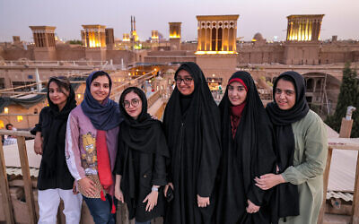 Des femmes posant avec des "badirs" (attrape-vent en farsi) qui ponctuent l'horizon derrière elles, sur le toit d'un bâtiment dans la ville centrale de Yazd, en Iran, le 3 juillet 2023. (Crédit : Atta Kenare/AFP)