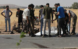 Des passants et des hommes armés se rassemblent autour d'un corps sur le site d'une attaque de drone dans la ville de Bzaah près d'al-Bab dans le gouvernorat d'Alep en Syrie, le 7 juillet 2023. (Crédit : Bakr ALKASEM / AFP)