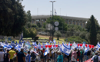 Des manifestants brandissant des drapeaux d'Israël lors d'un rassemblement devant la Knesset, à Jérusalem, le 11 juillet 2023. (Crédit : Menahem Kahana/AFP)