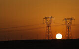 Le soleil se couche derrière les pylônes de transmission à haute tension (pylônes électriques) le long d'une autoroute à El-Shorouk, une ville satellite située à environ 47 kilomètres du centre-ville du Caire, le 24 juillet 2023. (Crédit : Khaled Desouki/AFP)