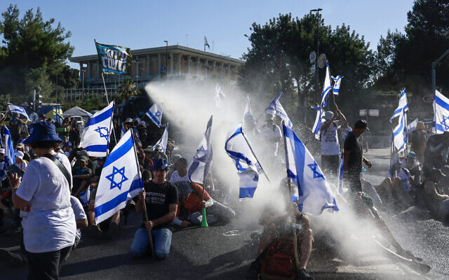 Des membres des forces de sécurité israéliennes utilisent un canon à eau pour disperser des manifestants bloquant une entrée de la Knesset à Jérusalem, le 24 juillet 2023. (Menahem KAHANA / AFP)