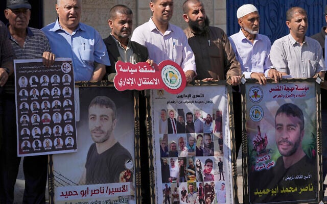 Illustration : Des manifestants portant des photos de divers prisonniers palestiniens, à gauche et au centre, qui sont détenus en détention administrative et des affiches du prisonnier Nasser Abu Hmeid, à droite et deuxième à gauche, qui serait gravement malade et qui purge plusieurs peines de prison à vie et 50 ans supplémentaires, lors d'une manifestation contre la politique israélienne de détention administrative et de soutien aux prisonniers palestiniens dans les prisons israéliennes, devant le bureau du Haut-Commissariat des Nations Unies aux droits de l'Homme dans la ville de Gaza, le 12 octobre 2022. Sur la banderole rouge, on peut lire en arabe : "A bas la détention administrative". (Crédit : AP Photo/Adel Hana) Illustration : Des manifestants portant des photos de divers prisonniers palestiniens, à gauche et au centre, qui sont détenus en détention administrative et des affiches du prisonnier Nasser Abu Hmeid, à droite et deuxième à gauche, qui serait gravement malade et qui purge plusieurs peines de prison à vie et 50 ans supplémentaires, lors d'une manifestation contre la politique israélienne de détention administrative et de soutien aux prisonniers palestiniens dans les prisons israéliennes, devant le bureau du Haut-Commissariat des Nations Unies aux droits de l'Homme dans la ville de Gaza, le 12 octobre 2022. Sur la banderole rouge, on peut lire en arabe : "A bas la détention administrative". (Crédit : AP Photo/Adel Hana)
