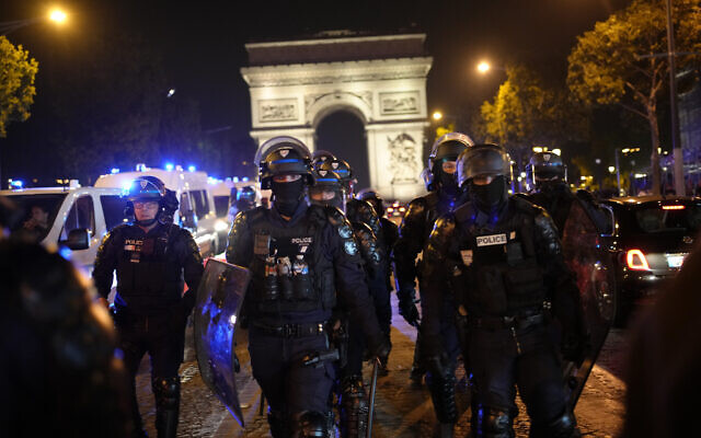 Des policiers patrouillant devant l'Arc de Triomphe sur les Champs Elysées, à Paris, le 1er juillet 2023. (Crédit : AP/Christophe Ena)