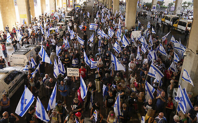 Des Israéliens protestant contre les projets du gouvernement du Premier ministre Benjamin Netanyahu de réformer le système judiciaire, à l'aéroport Ben Gurion près de Tel Aviv, le 3 juillet 2023. (Crédit : AP Photo/ Ohad Zwigenberg)
