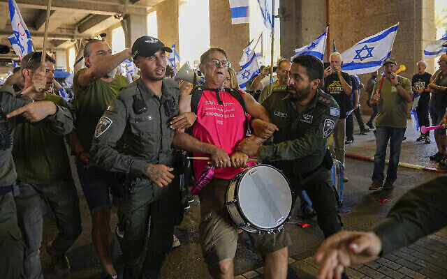 Des policiers israéliens arrêtent un homme lors d'une manifestation contre les plans du gouvernement du Premier ministre Benjamin Netanyahu visant à remanier le système judiciaire, à l'aéroport Ben Gurion, le lundi 3 juillet 2023. (Crédit : AP Photo/Ohad Zwigenberg)