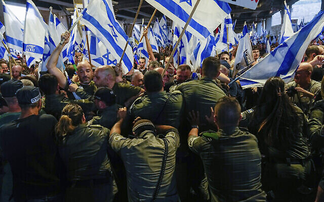 Des agents de la police des frontières israélienne essaient de disperser des manifestants qui tentent de bloquer l'entrée du principal aéroport international d'Israël lors d'une manifestation contre les projets du gouvernement du Premier ministre Benjamin Netanyahu visant à remanier en profondeur le système judiciaire, à l'aéroport Ben Gurion, le 3 juillet 2023. (Crédit : AP Photo/ Ohad Zwigenberg)