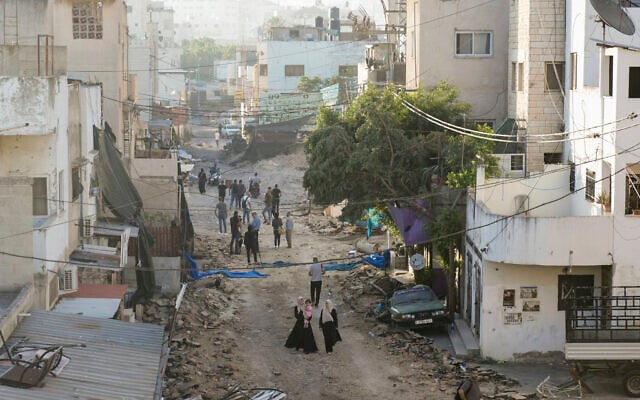 Des Palestiniens marchant sur une route endommagée, après que l'armée israélienne a retiré ses forces du bastion terroriste, dans le camp de réfugiés de Jénine, en Cisjordanie, le 5 juillet 2023. (Crédit : AP Photo/Majdi Mohamed)