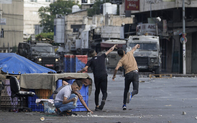 Des Palestiniens affrontant les forces de sécurité israéliennes lors d'un raid militaire dans la ville cisjordanienne de Naplouse, le 7 juillet 2023. (Crédit : AP Photo/Majdi Mohammed) Des Palestiniens affrontant les forces de sécurité israéliennes lors d'un raid militaire dans la ville cisjordanienne de Naplouse, le 7 juillet 2023. (Crédit : AP Photo/Majdi Mohammed)