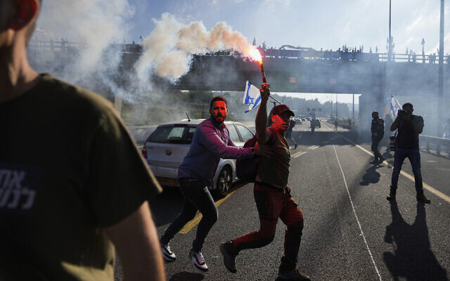 Des policiers israéliens dispersent des manifestants qui bloquent une autoroute menant à Jérusalem, lors d'une manifestation contre les projets du nouveau gouvernement du Premier ministre Benjamin Netanyahu visant à réformer le système judiciaire, le 11 juillet 2023. (Crédit : AP Photo/Ohad Zwigenberg)