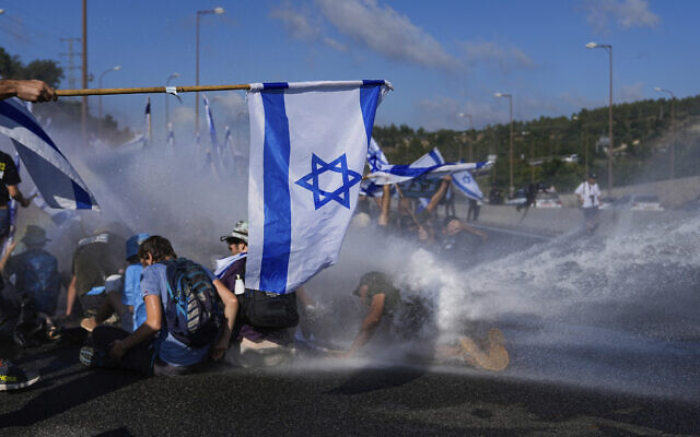 Des policiers israéliens dispersent des manifestants qui bloquent une autoroute menant à Jérusalem, lors d'une manifestation contre les projets du nouveau gouvernement du Premier ministre Benjamin Netanyahu visant à réformer le système judiciaire, le 11 juillet 2023. (Crédit : AP Photo/Ohad Zwigenberg)
