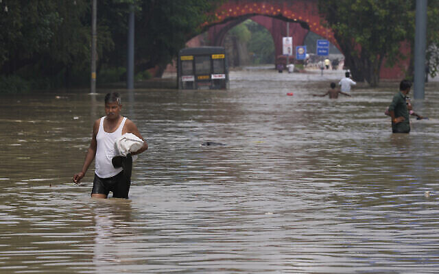 Des personnes se fraient un chemin dans une rue inondée suite aux très fortes pluies enregistrées à New Delhi, en Inde, le jeudi 13 juillet 2023. (Crédit : AP/Manish Swarup) Des personnes se fraient un chemin dans une rue inondée suite aux très fortes pluies enregistrées à New Delhi, en Inde, le jeudi 13 juillet 2023. (Crédit : AP/Manish Swarup)
