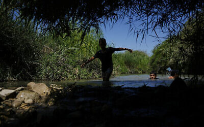 Des enfants se rafraîchissent dans les sources d'Ein Aviel près d'Aviel, en Israël, le jeudi 13 juillet 2023. (Crédit : AP/Ariel Schalit)