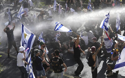La police israélienne utilisant un canon à eau pour disperser les manifestants qui bloquent une route lors d'un rassemblement contre les plans du gouvernement du Premier ministre Benjamin Netanyahu visant à remanier le système judiciaire, à Jérusalem, le 24 juillet 2023. (Crédit : Mahmoud Illean/AP Photo)