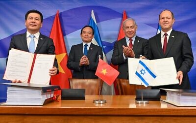 Le ministre de l'Économie Nir Barkat, à droite, et son homologue vietnamien Nguyen Hong Dien, à gauche, brandissant des copies de l'accord de libre-échange signé, sous les applaudissements du Premier ministre Benjamin Netanyahu, 2e à droite, et du vice-Premier ministre vietnamien Tran Luu Quang, au Bureau du Premier ministre ,à Jérusalem, le 25 juillet 2023. (Crédit : Kobi Gideon/GPO)