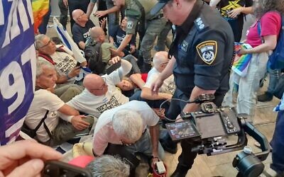 La police tentant de faire sortir de force des manifestants du hall d'arrivée de l'aéroport Ben Gurion, le 3 juillet 2023. (Crédit : Esther Wainer-Iluz)
