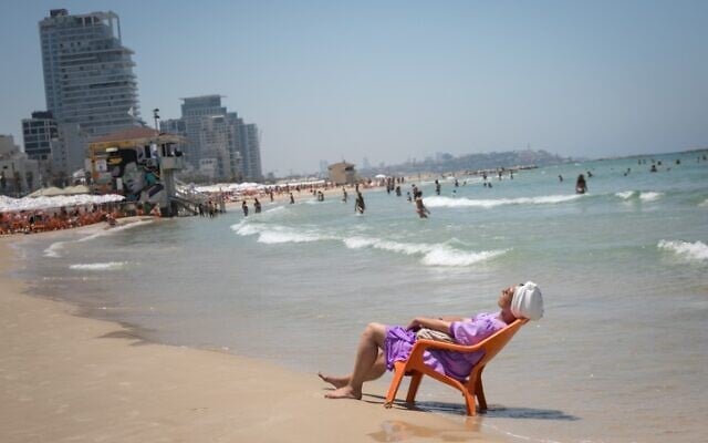 Des Israéliens et des touristes profitant de la plage alors qu'une vague de chaleur frappe le pays, à Tel Aviv, le 17 juillet 2023. (Crédit : Miriam Alster/FLASH90)