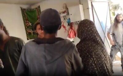 Des résidents d'implantations armés fouillant une maison palestinienne dans un village bédouin du sud des collines de Hébron, le 25 juillet 2023. (Crédit : Capture d'écran Yesh Din)