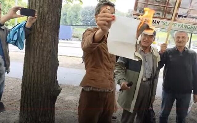 Une femme brûlant une feulle de papier devant l'ambassade d'Israël, à Stockholm, le 28 juillet 2023. (Crédit : Capture d'écran Hedlund Media TV ; utilisée conformément à la clause 27a de la loi sur les droits d'auteur) Une femme brûlant une feulle de papier devant l'ambassade d'Israël, à Stockholm, le 28 juillet 2023. (Crédit : Capture d'écran Hedlund Media TV ; utilisée conformément à la clause 27a de la loi sur les droits d'auteur)