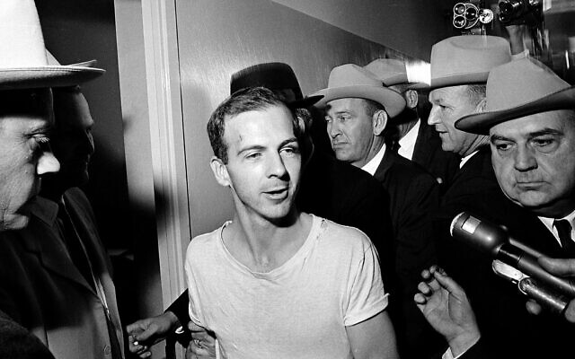 Sur cette photo d'archives, Lee Harvey Oswald, entouré d'inspecteurs, s'adresse aux médias alors qu'il est conduit, pour une nouvelle série d'interrogatoires dans le cadre de l'assassinat du président américain John F. Kennedy, dans un couloir du commissariat de Dallas le du 23 novembre 1963. (Crédit : AP)