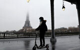 Une femme en trottinette devant la tour Eiffel, à Paris, le 27 janvier 2021. (Crédit : LUDOVIC MARIN/AFP)