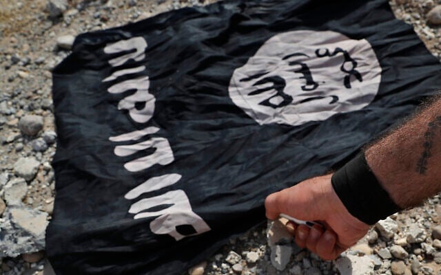 Un combattant d'une milice chrétienne syriaque qui combat l'État islamique sous la bannière des Forces démocratiques syriennes, appuyées par les États-Unis, brûlant un drapeau de l'organisation terroriste à l'Ouest de Raqqa, sur la ligne de front du nord-est de la Syrie, le 17 juillet 2017. (Crédit : Hussein Malla/ AP Photo/Dossier) Un combattant d'une milice chrétienne syriaque qui combat l'État islamique sous la bannière des Forces démocratiques syriennes, appuyées par les États-Unis, brûlant un drapeau de l'organisation terroriste à l'Ouest de Raqqa, sur la ligne de front du nord-est de la Syrie, le 17 juillet 2017. (Crédit : Hussein Malla/ AP Photo/Dossier)