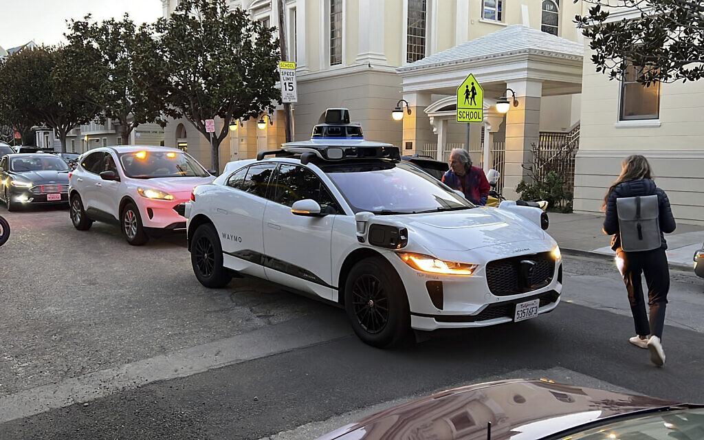 Des passagers tentant de comprendre pourquoi un taxi sans chauffeur Waymo ne bouge pas alors que la circulation s’intensifie derrière lui, à San Francisco, le 15 février 2023. (Crédit : Terry Chea/AP Photo)