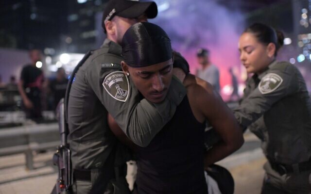 La police dispersant un manifestant d'une route principale lors d'une manifestation contre la gestion par les forces de l'ordre d'une enquête sur un délit de fuite à Netanya dans lequel un garçon de 4 ans a été tué, à Tel Aviv, le 23 août 2023. (Crédit : Tomer Neuberg/Flash90)