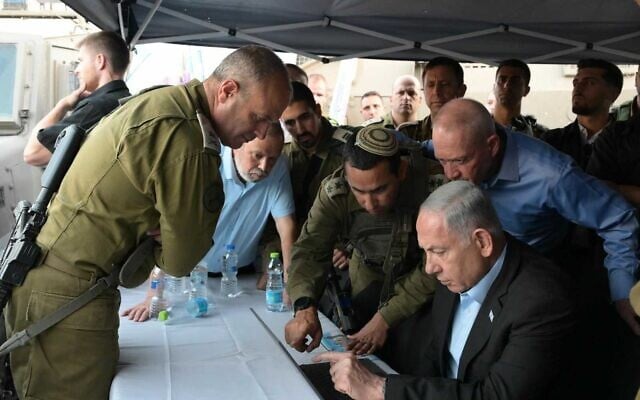 Le Premier ministre Benjamin Netanyahu et le ministre de la Défense  Yoav Gallant, à droite, sur les lieux d'une attaque terroriste à l'arme à feu près de Hébron, en Cisjordanie, le 21 août 2023. (Crédit :  Amos Ben Gershom/GPO)
