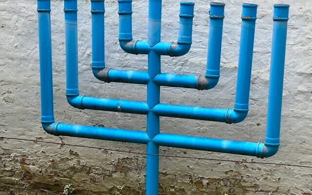 Une menorah artisanale à neuf branches fabriquée à partir de tuyaux d'eau recyclés, installée à l'extérieur de la synagogue de Novi Sad, en Serbie (Crédit : Larry Luxner/JTA)