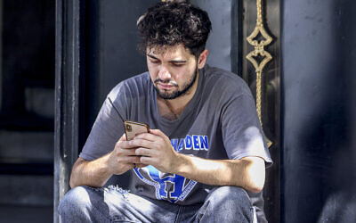 Illustration : Une personne tenant un téléphone, à Téhéran, le 11 septembre 2023. (Crédit : Atta Kenare/AFP)