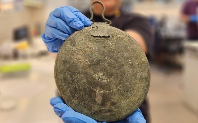 Un rare miroir en bronze découvert dans la tombe d'une courtisane grecque, le long de la route de Hébron à Jérusalem, dans une photo publiée le 27 septembre 2023. (Crédit : Yoli Schwartz/Israel Antiquities Authority) Un rare miroir en bronze découvert dans la tombe d'une courtisane grecque, le long de la route de Hébron à Jérusalem, dans une photo publiée le 27 septembre 2023. (Crédit : Yoli Schwartz/Israel Antiquities Authority)