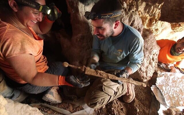 Des archéologues retirant les épées de l'anfractuosité de la roche où elles étaient cachées il y a environ 1 900 ans dans une grotte du désert de Judée. (Crédit : Emil Aladjem/IAA) Des archéologues retirant les épées de l'anfractuosité de la roche où elles étaient cachées il y a environ 1 900 ans dans une grotte du désert de Judée. (Crédit : Emil Aladjem/IAA)