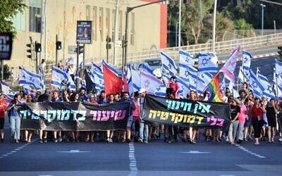 Des manifestants contre la refonte judiciaire de la coalition, portant des pancartes sur lesquelles on peut lire : "Il n'y a pas d'éducation sans démocratie", à droite, et "Une leçon de démocratie", dans la ville centrale de Rehovot, le 2 septembre 2023. (Crédit : Roby Yahav)