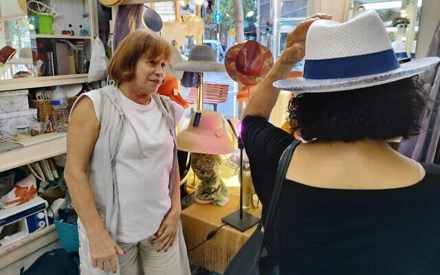 Dalia Varman (à gauche) regarde une cliente essayer un chapeau, dans sa boutique Les Chapeaux de Dalia, à Tel Aviv. (Crédit : Gavriel Fiske/Times of Israel)