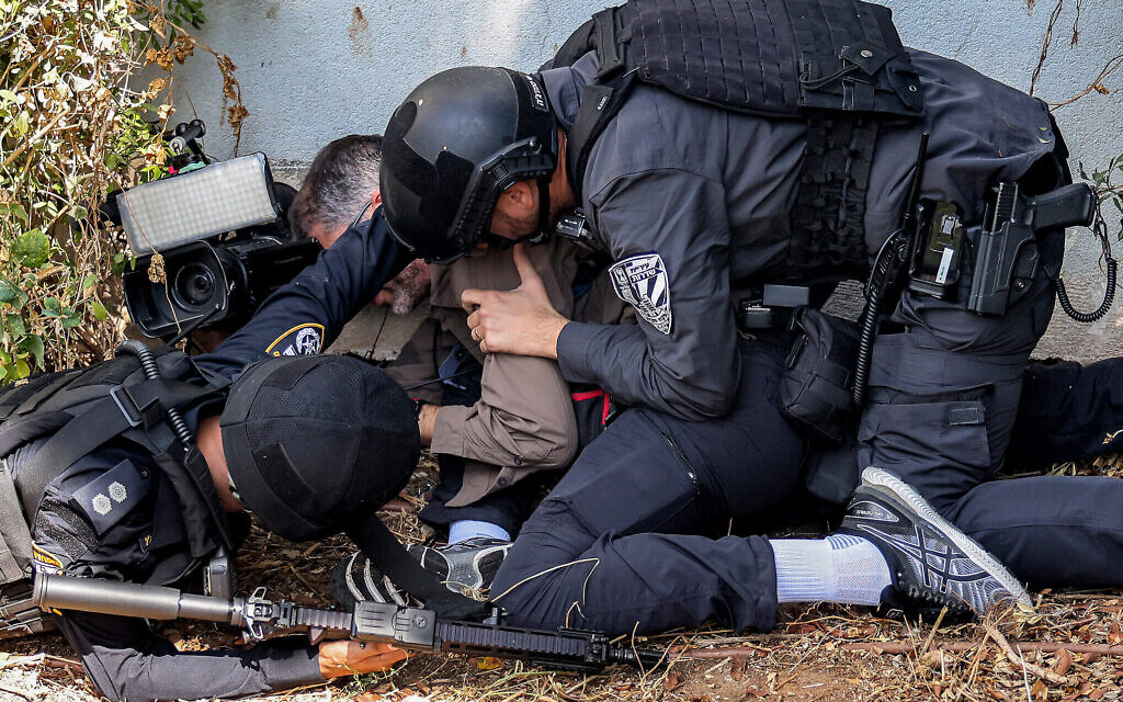 Les forces de sécurité aident un journaliste à se mettre à couvert lors d'une alerte à la roquette, à Sderot, le 12 octobre 2023. (Crédit : Menahem KAHANA / AFP)