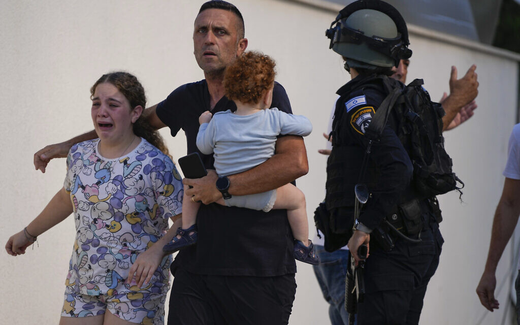 Des policiers israéliens évacuent une famille d'un site touché par une roquette tirée depuis la bande de Gaza, à Ashkelon, dans le sud d'Israël, le 7 octobre 2023. (Crédit : Tsafrir Abayov/AP)
