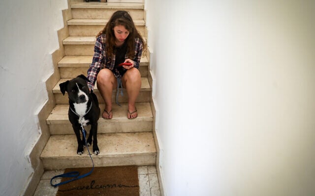 Une femme et son chien se réfugieant dans un escalier à Jérusalem, alors qu'une sirène d'alerte retentit pendant une salve de roquettes tirée de Gaza sur Israël, le 7 octobre 2023. (Crédit : Noam Revkin Fenton/Flash90) Une femme et son chien se réfugieant dans un escalier à Jérusalem, alors qu'une sirène d'alerte retentit pendant une salve de roquettes tirée de Gaza sur Israël, le 7 octobre 2023. (Crédit : Noam Revkin Fenton/Flash90)