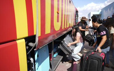 Des Israéliens chargeant leurs affaires dans un bus lors de leur évacuation de la ville de Sderot, dans le sud d'Israël, le 15 octobre 2023 (Crédit : Ariel Schalit/AP)