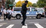 Illustration : Un homme marchant alors que la police patrouille dans un quartier de Brooklyn où vit une importante communauté juive orthodoxe, à New York, le 12 octobre 2023. (Crédit : Spencer Platt/Getty Images/AFP)