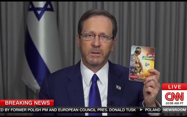 Le président Isaac Herzog montrant un manuel d'enlèvement et de torture prélevé sur le corps d'un terroriste du Hamas lors d'une interview accordée à CNN le 15 octobre 2023. (Crédit : Capture d'écran CNN)